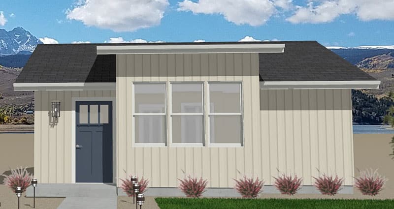 Holiday-ADU-Front-Elevation A small, modern beige cottage with vertical siding, three front windows, a dark gray door, and a black roof, set against a mountainous background under a partly cloudy sky. Shrubs and a lawn line the front walkway.