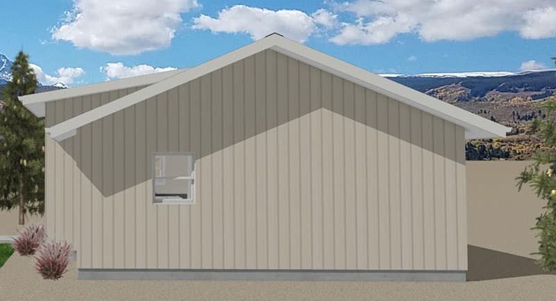 Holiday-ADU-Right-Elevation A beige metal building with a gabled roof, a small window on the side, some shrubs in front, and a backdrop of mountains, trees, and a partly cloudy sky.